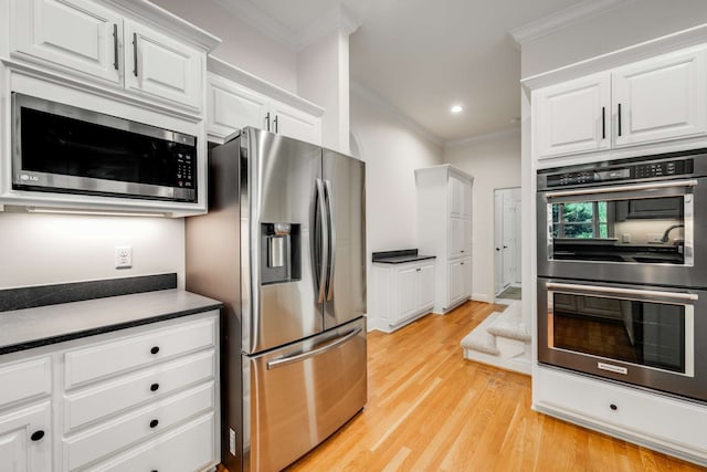 kitchen with light wood-type flooring, appliances with stainless steel finishes, crown molding, and white cabinets