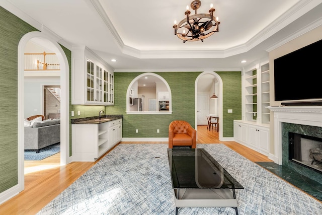 interior space featuring sink, a fireplace, crown molding, light wood-type flooring, and built in features