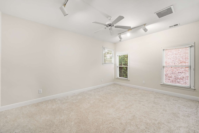 carpeted empty room featuring ceiling fan, rail lighting, and plenty of natural light