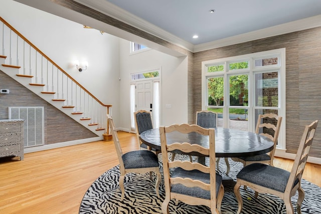 dining area featuring a high ceiling, wood-type flooring, and crown molding