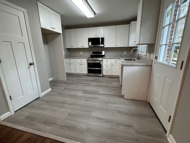 kitchen with white cabinetry, light wood-type flooring, stainless steel appliances, and sink