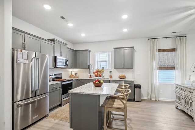 kitchen with stainless steel appliances, tasteful backsplash, a kitchen breakfast bar, light hardwood / wood-style flooring, and a kitchen island