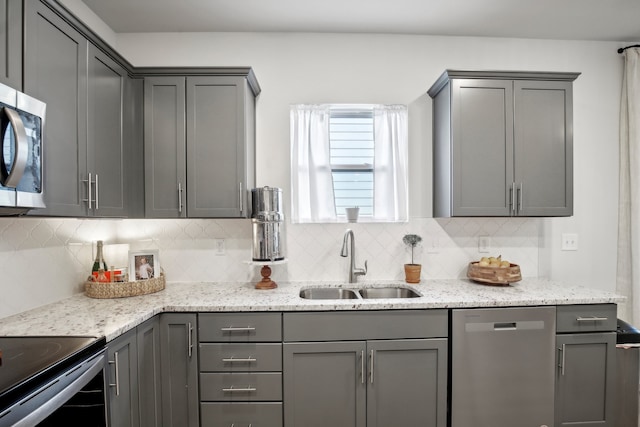 kitchen featuring gray cabinetry, light stone countertops, appliances with stainless steel finishes, and sink