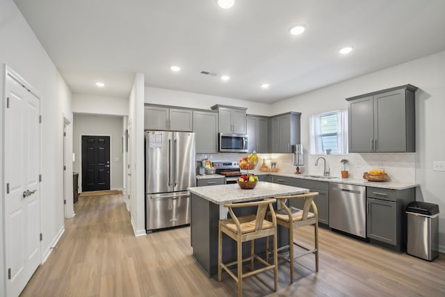 kitchen featuring stainless steel appliances, light hardwood / wood-style floors, sink, and light stone counters