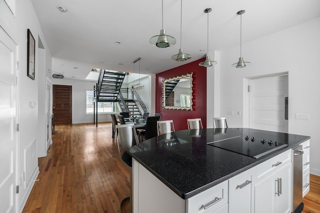 kitchen featuring black electric cooktop, hardwood / wood-style flooring, a center island, white cabinets, and pendant lighting