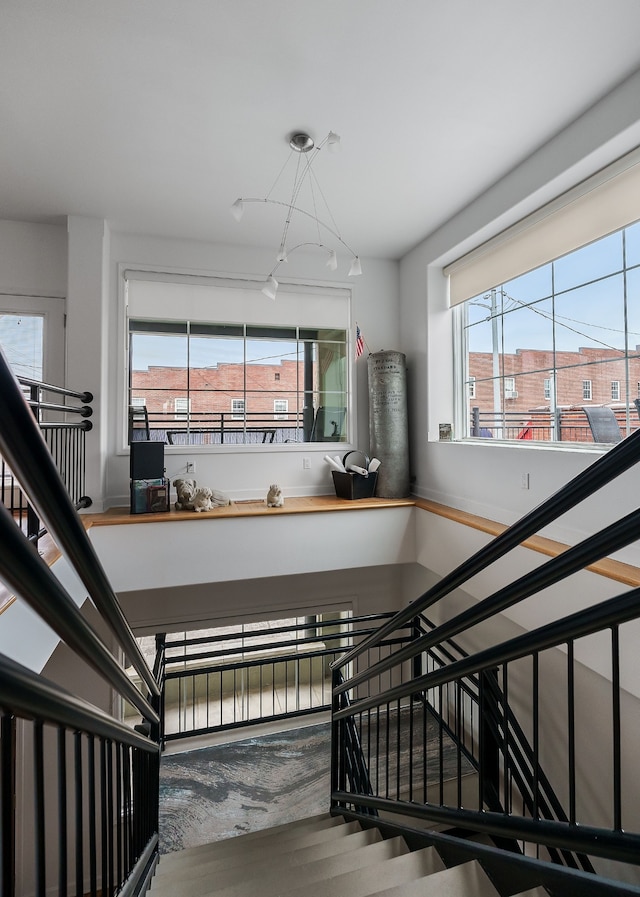 staircase with an inviting chandelier, hardwood / wood-style floors, and a healthy amount of sunlight