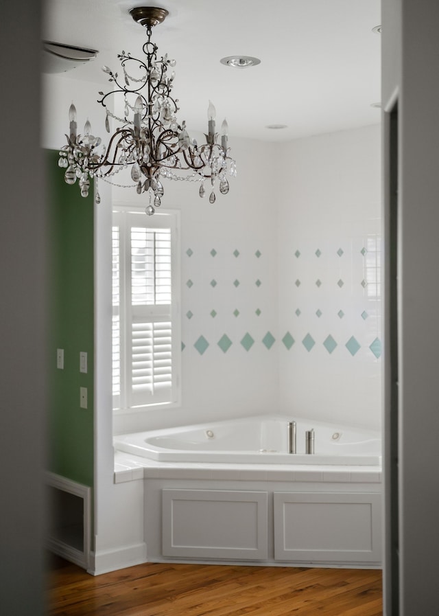 bathroom featuring hardwood / wood-style flooring, a tub to relax in, and an inviting chandelier