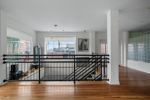 corridor with hardwood / wood-style flooring, plenty of natural light, and a notable chandelier