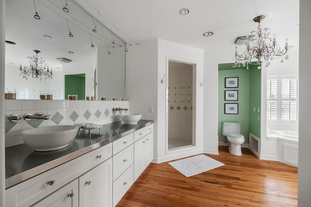 full bathroom featuring wood-type flooring, separate shower and tub, toilet, an inviting chandelier, and vanity