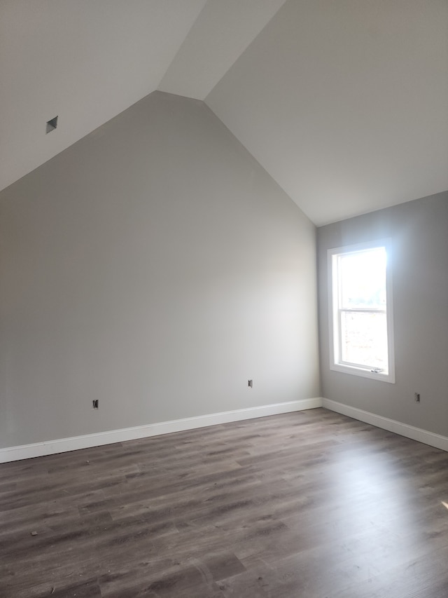 additional living space featuring dark wood-type flooring and vaulted ceiling