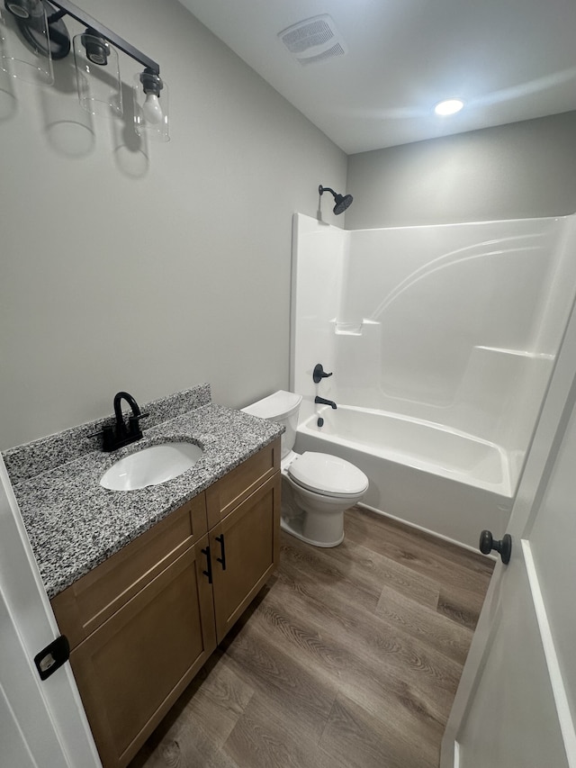 full bathroom with hardwood / wood-style flooring, vanity, toilet, and shower / washtub combination