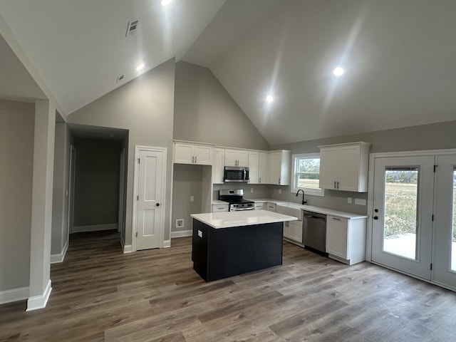 kitchen with white cabinetry, appliances with stainless steel finishes, light hardwood / wood-style floors, and a kitchen island