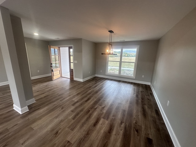 unfurnished dining area with dark wood-type flooring and a chandelier