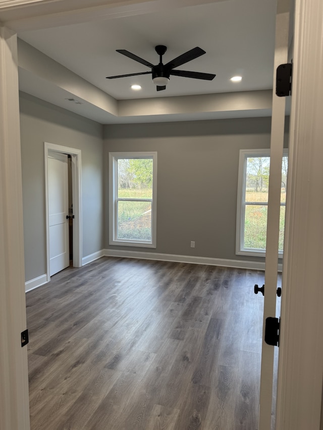 unfurnished room featuring plenty of natural light, dark hardwood / wood-style floors, and ceiling fan