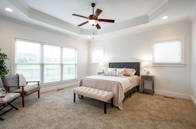 carpeted bedroom with ceiling fan, ornamental molding, and a tray ceiling