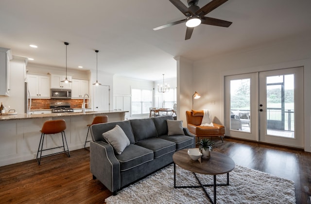 living room with plenty of natural light, dark hardwood / wood-style floors, sink, and ceiling fan with notable chandelier