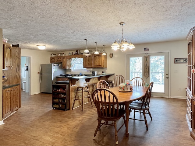 dining room featuring hardwood / wood-style flooring, a textured ceiling, and a chandelier