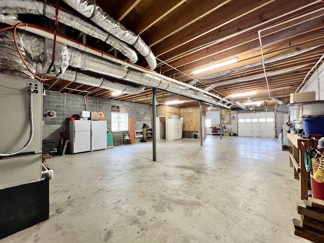 basement featuring washing machine and clothes dryer and white fridge