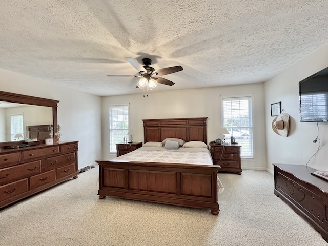 bedroom featuring light colored carpet, a textured ceiling, and ceiling fan