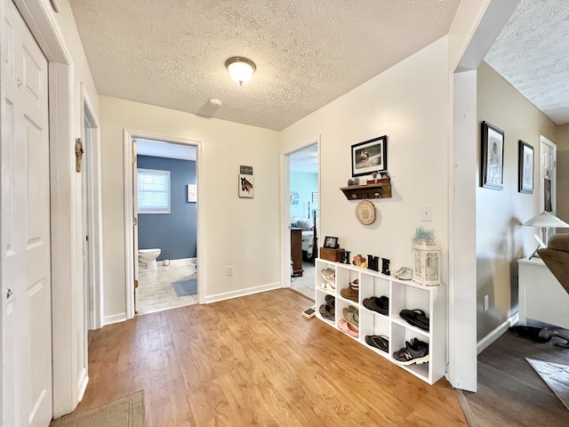 hall featuring a textured ceiling and light hardwood / wood-style flooring