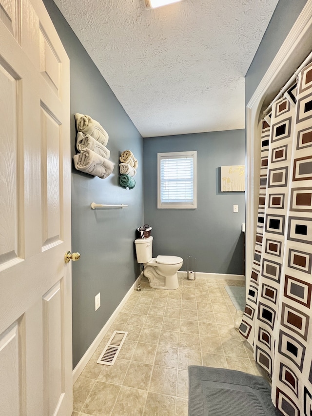 bathroom featuring tile patterned floors, toilet, and a textured ceiling