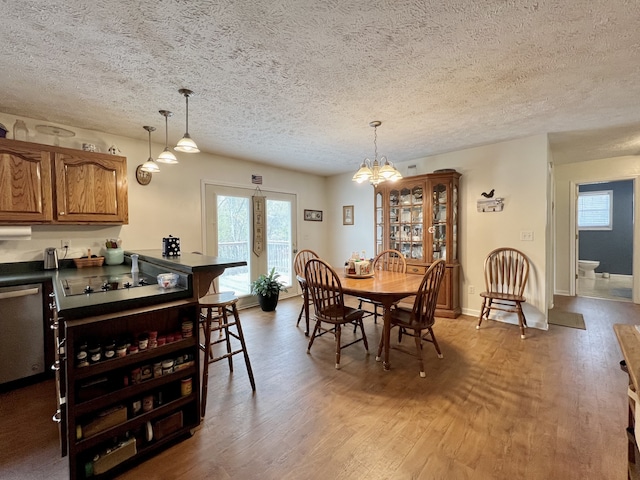 dining area with hardwood / wood-style flooring, a notable chandelier, and a textured ceiling