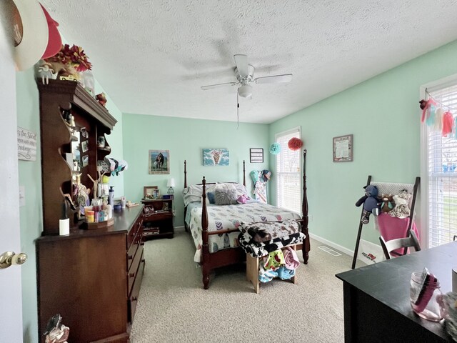 bedroom featuring ceiling fan, light colored carpet, and a textured ceiling