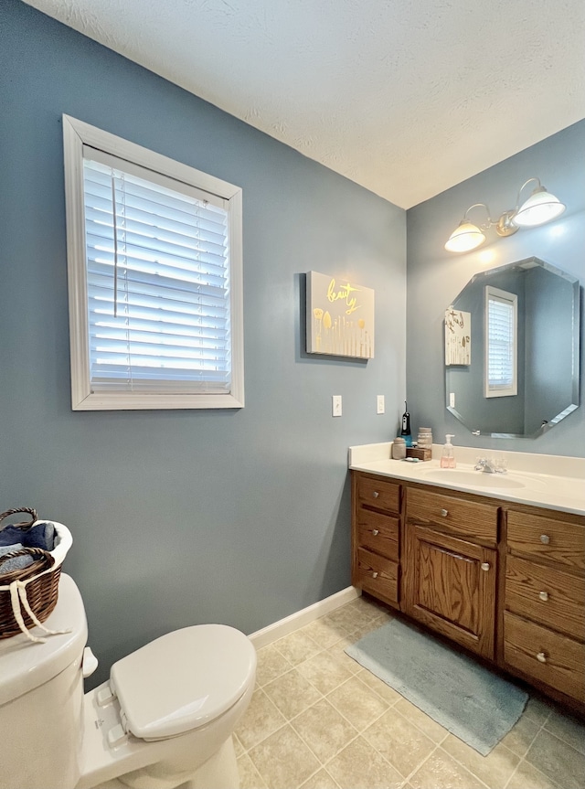 bathroom featuring vanity, plenty of natural light, tile patterned floors, and toilet