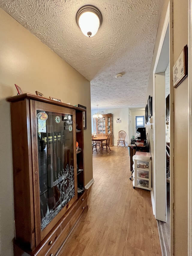 hall with wood-type flooring and a textured ceiling