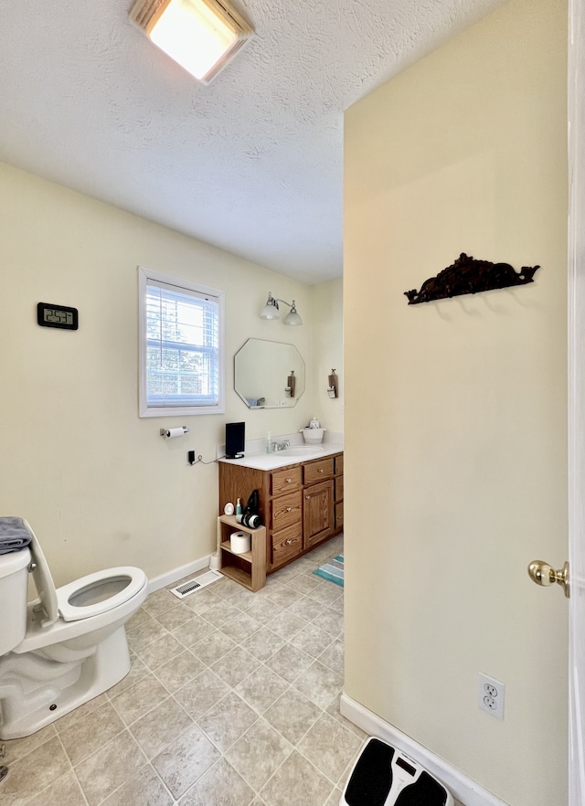 bathroom with vanity, a textured ceiling, and toilet