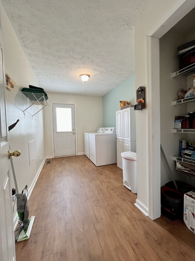 laundry area with independent washer and dryer, cabinets, a textured ceiling, and light wood-type flooring