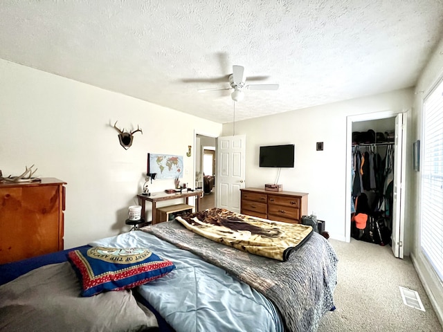 bedroom featuring ceiling fan, light carpet, a textured ceiling, and a closet