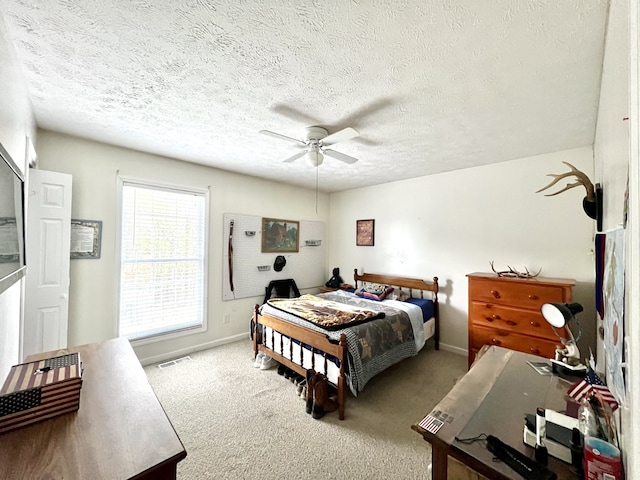 carpeted bedroom featuring a textured ceiling and ceiling fan