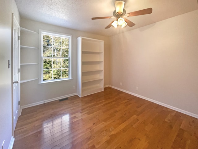 empty room featuring a textured ceiling, wood-type flooring, and ceiling fan