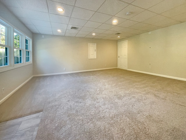 carpeted empty room featuring a drop ceiling