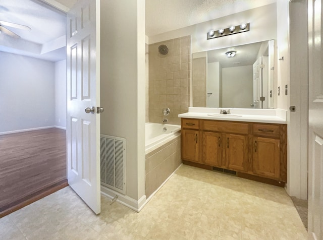 bathroom featuring hardwood / wood-style flooring, ceiling fan, vanity, and tiled shower / bath combo