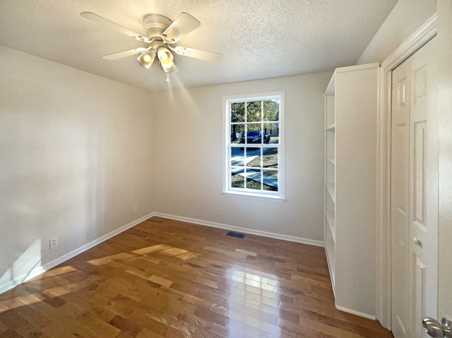 unfurnished room featuring ceiling fan, dark hardwood / wood-style floors, and a textured ceiling