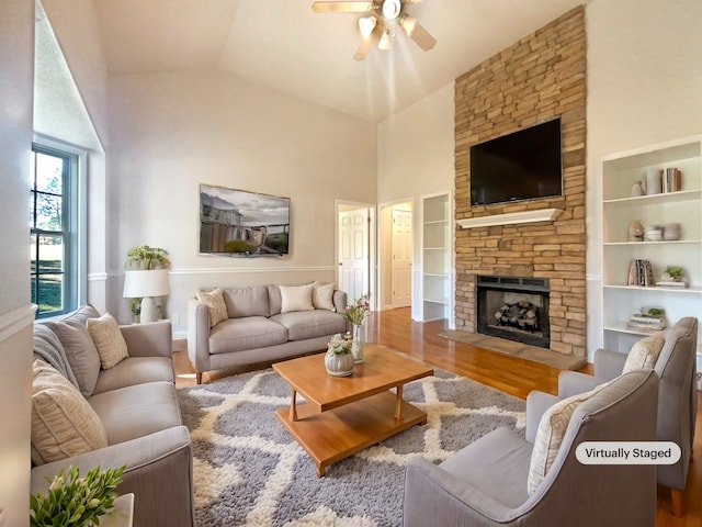 living room with built in shelves, ceiling fan, hardwood / wood-style floors, a fireplace, and vaulted ceiling