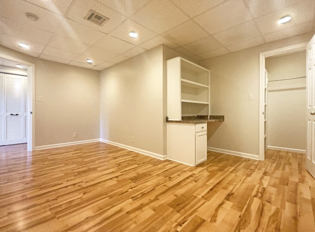 interior space featuring a drop ceiling and light hardwood / wood-style floors