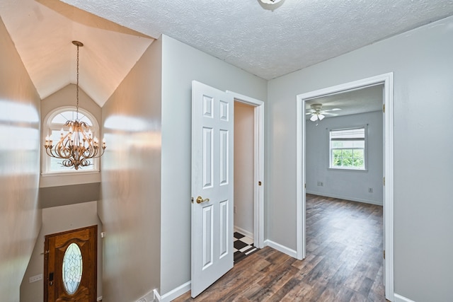 hallway with a textured ceiling, dark hardwood / wood-style floors, a chandelier, and vaulted ceiling