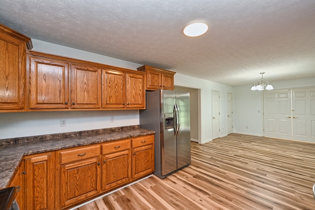 kitchen featuring hanging light fixtures, stainless steel fridge with ice dispenser, light wood-type flooring, and a notable chandelier