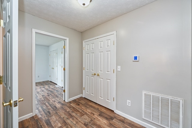 corridor with dark wood-type flooring and a textured ceiling