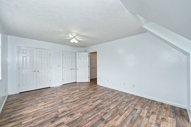 interior space featuring a textured ceiling, two closets, ceiling fan, and dark hardwood / wood-style floors