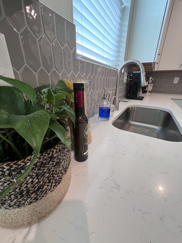 interior details featuring white cabinets, sink, and tasteful backsplash