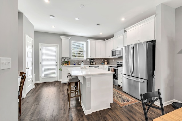 kitchen with stainless steel appliances, white cabinets, a kitchen island with sink, and dark hardwood / wood-style flooring