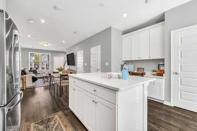 kitchen with white cabinetry, dark wood-type flooring, a center island, and stainless steel refrigerator