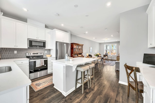 kitchen featuring a kitchen island, white cabinetry, appliances with stainless steel finishes, and dark hardwood / wood-style floors