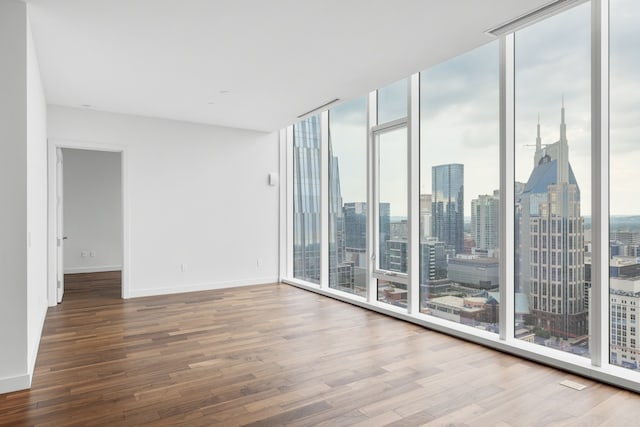 unfurnished room with hardwood / wood-style floors and floor to ceiling windows