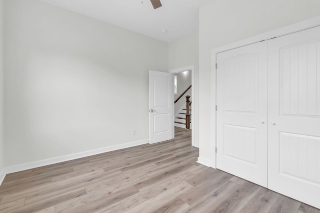 unfurnished bedroom featuring ceiling fan, a closet, and light wood-type flooring