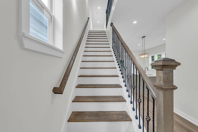 staircase featuring wood-type flooring and a notable chandelier